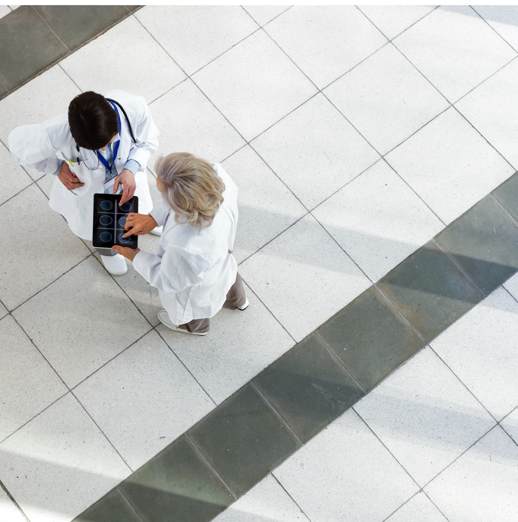 Hospital staff discussing patient care. The Doctors are using a digital tablet with the patient's chart.