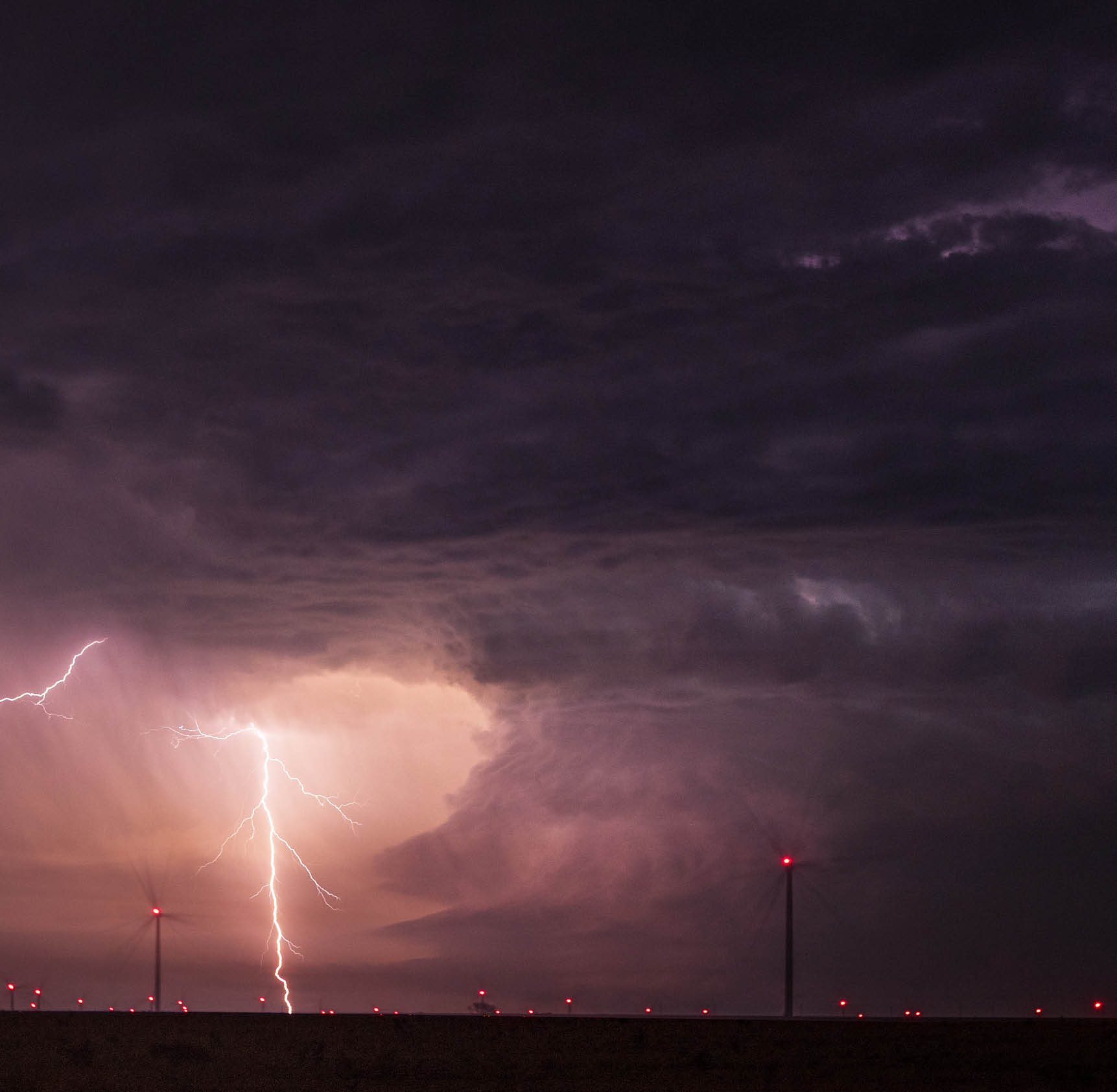 One of the most stunning supercell storms of the season. This night time supercell had almost constant lightning. This storm displays an astonishing mesocyclone twisting upwards with as mentioned very intense lightning. A wind farm can be seen in the foreground lit up with red lights which is a perfect combination to this epic scene.
