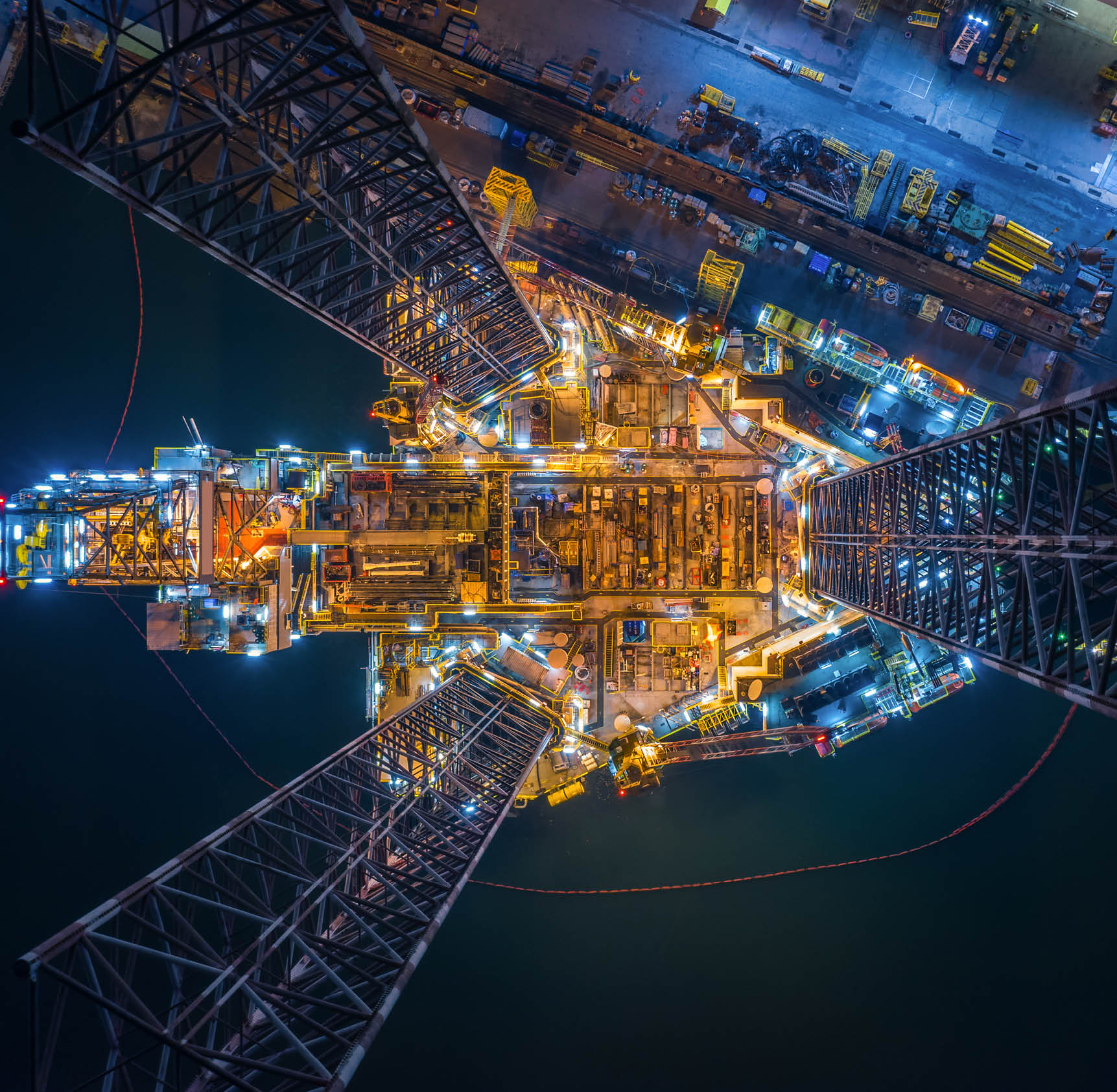 World at work drone view of Oil and gas jack-up rig at the yard for maintenance with many vessels, the petroleum rig is applied for producing oil and gas in offshore in the petroleum industry.